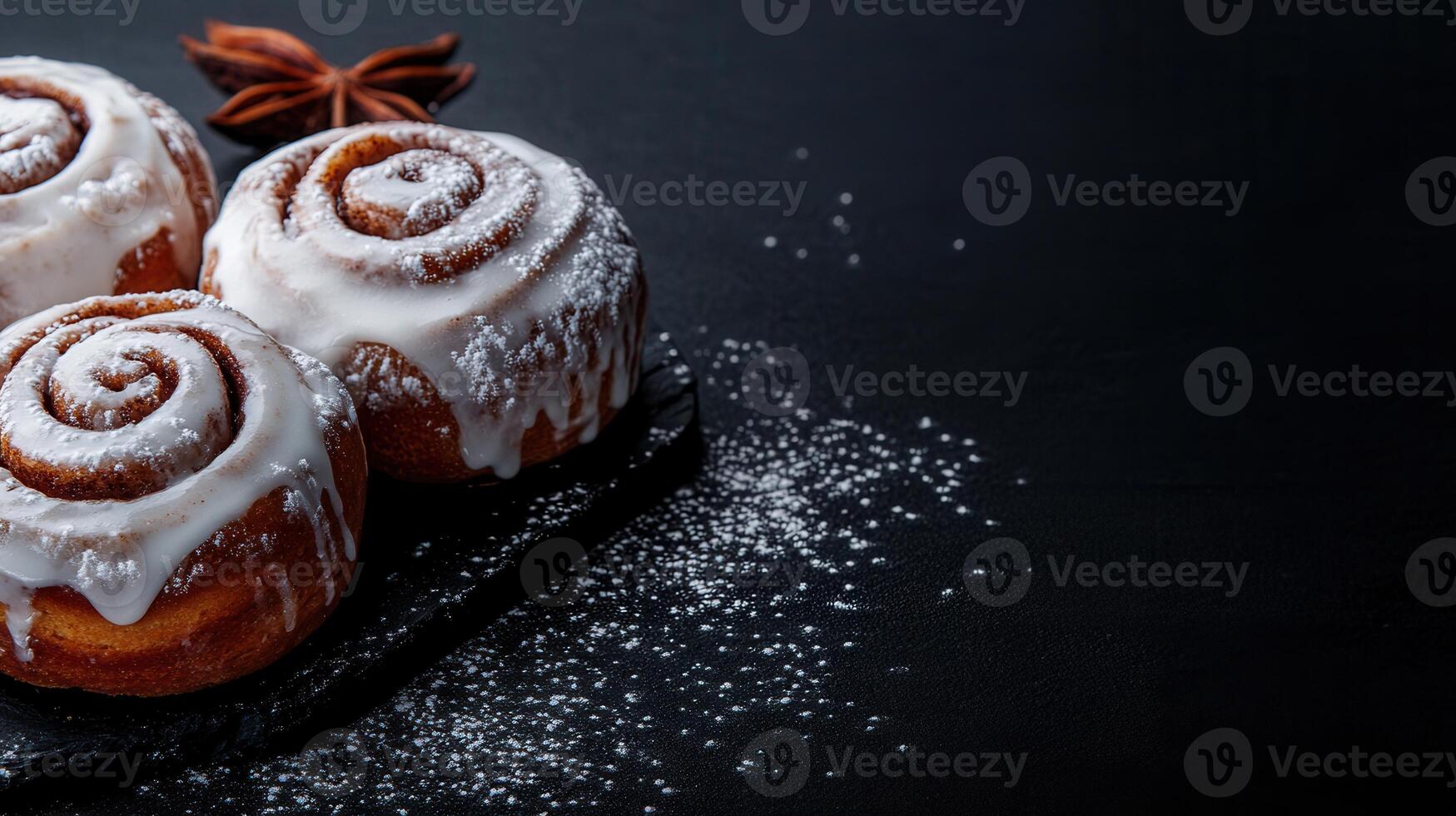 Three warm and delicious cinnamon rolls glazed to perfection on a striking black surface ready for sweet indulgence photo