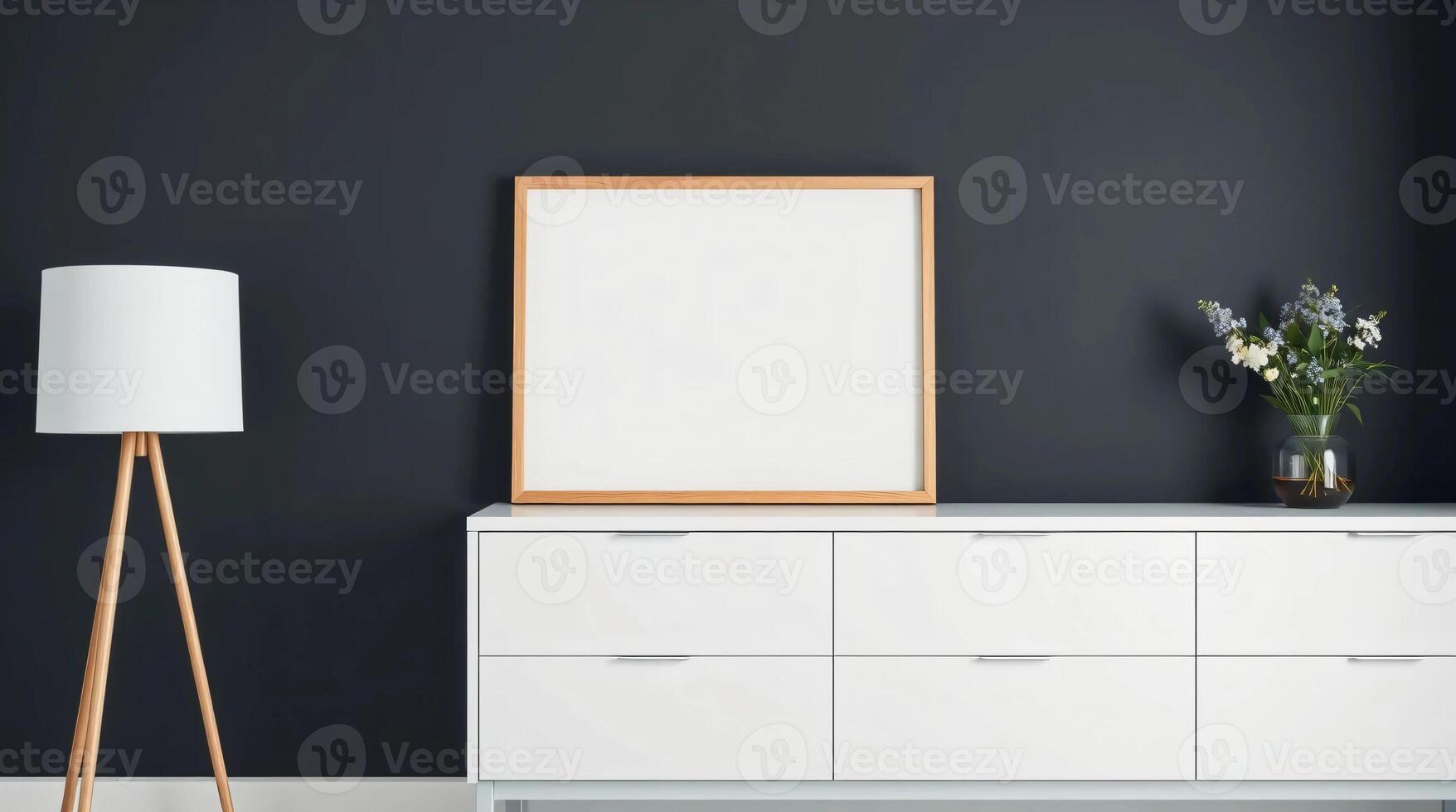A white dresser and a wooden lamp in front of a black wall photo