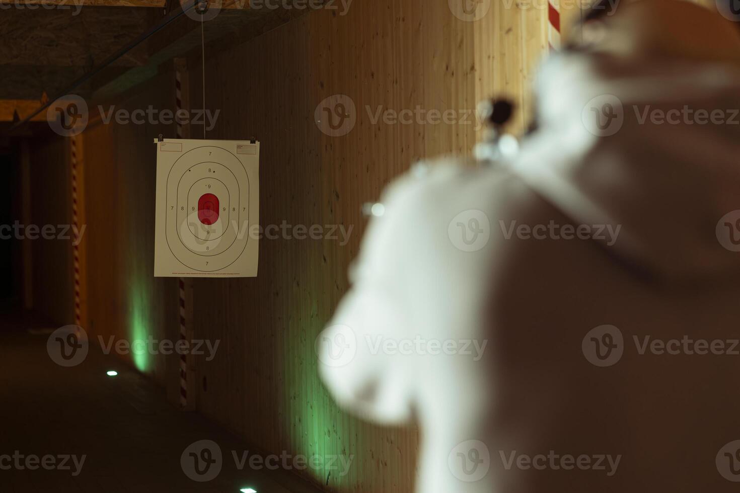 Man in shooting range using handgun to hit paper targets with ammunition. Close up shot of client at indoor firing range facility shooting bullseyes, enjoying using weapons during leisure time photo