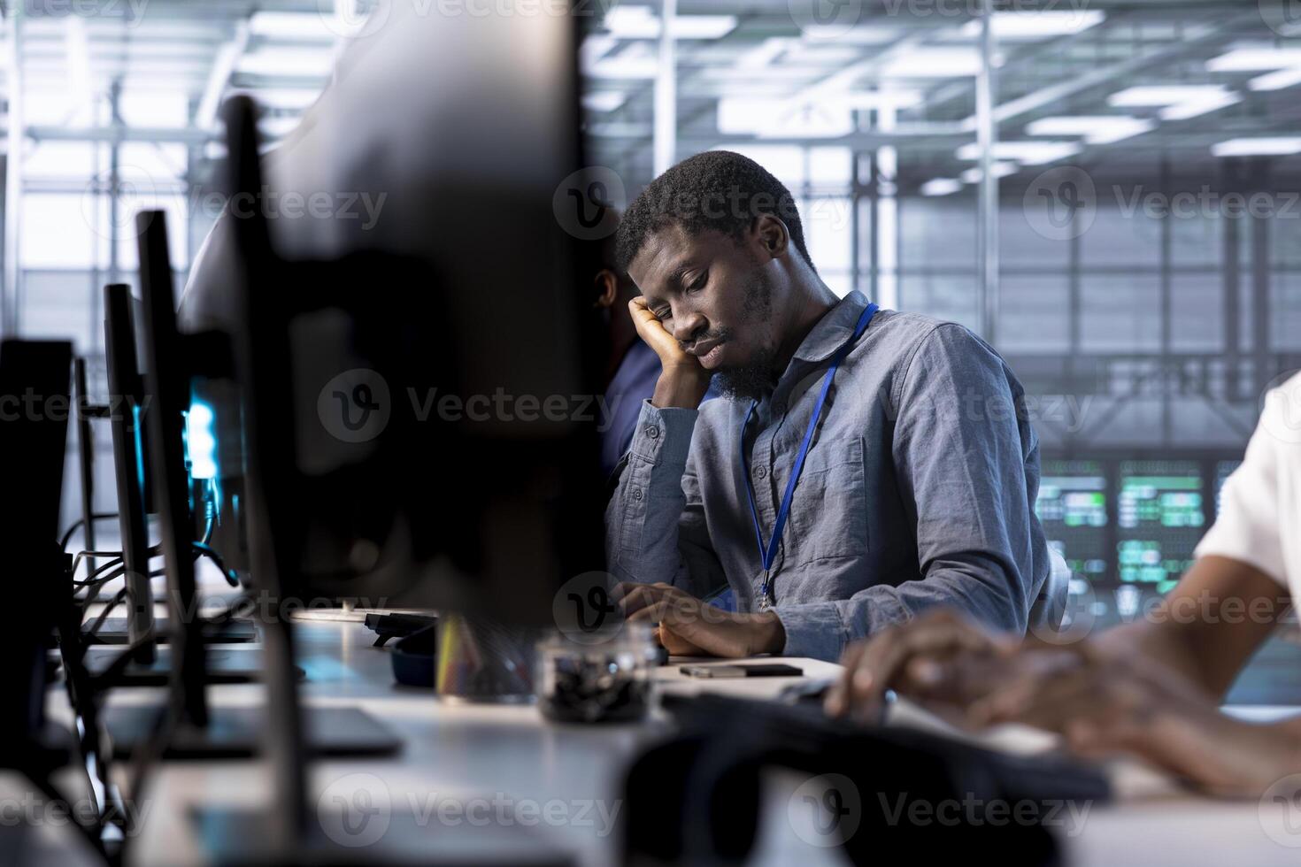 Bored data center engineer mindlessly using programming languages to construct algorithms and build applications. Fatigued server room employee tired of debugging and optimizing code photo