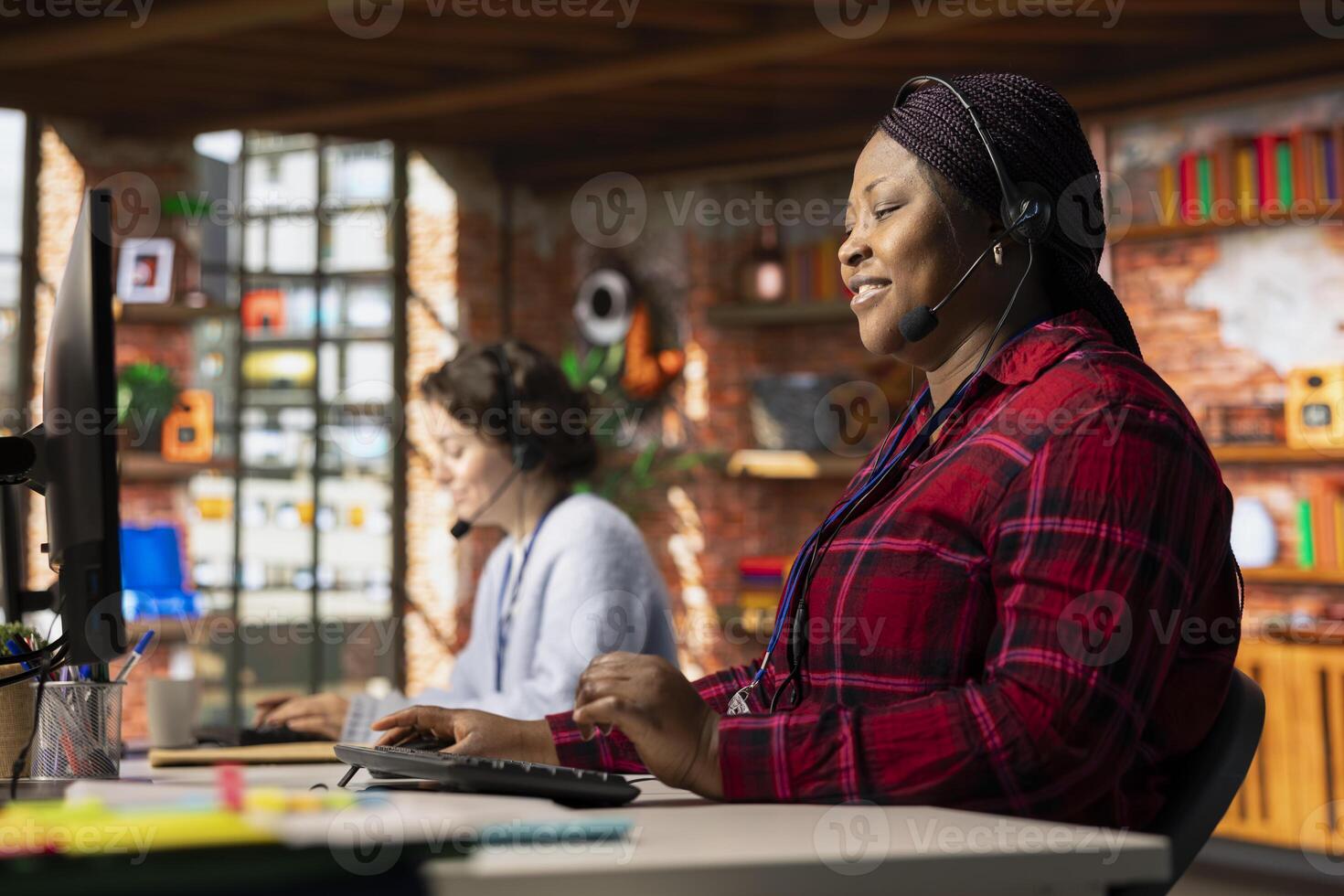 Cheerful call center operator talking in headset microphone, helping customers regain access to accounts and devices. Jolly customer center worker assisting clients needing help resetting password photo