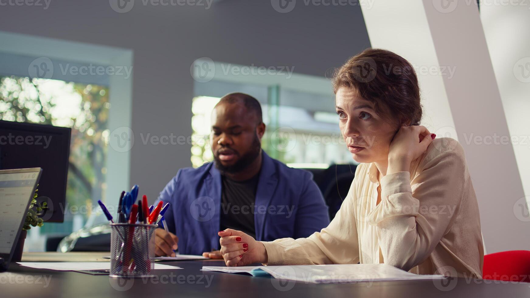 Car dealership salesman giving couple documentation to read after agreeing terms. Agent giving sale contract for clients to sign after they decide to make purchase, camera B photo