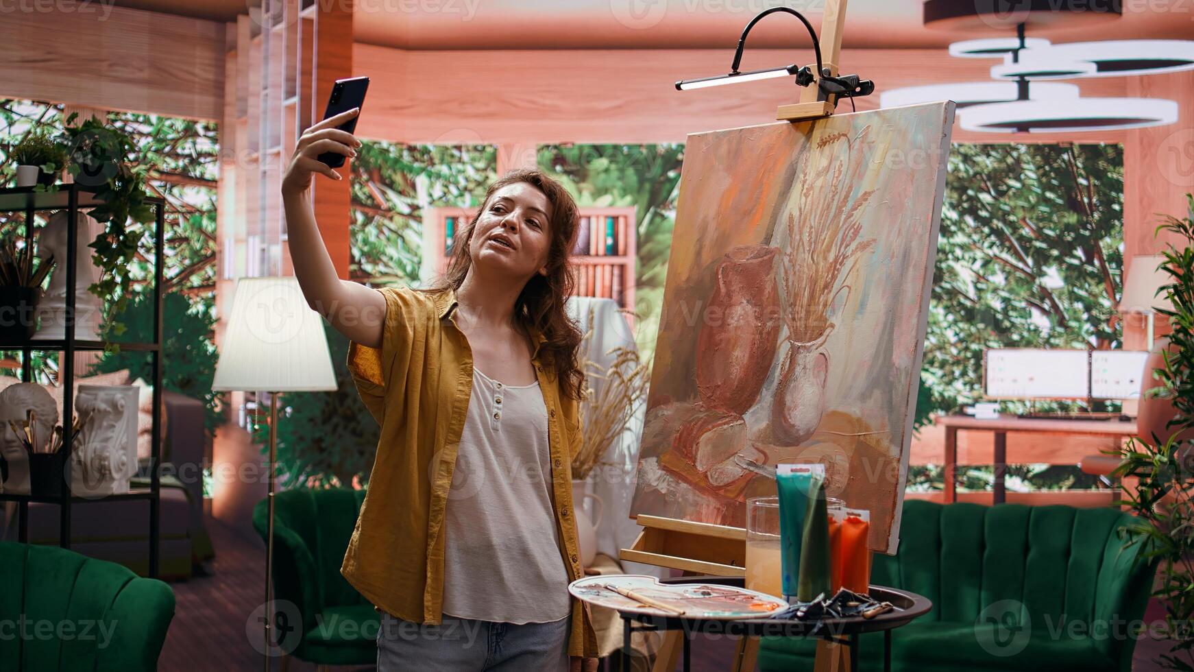 In modern atelier, artist filming rustic artwork painting with smartphone, social media branding. Recording and taking pictures of colorful canvas with watercolor piece, self promotion. Camera B. photo