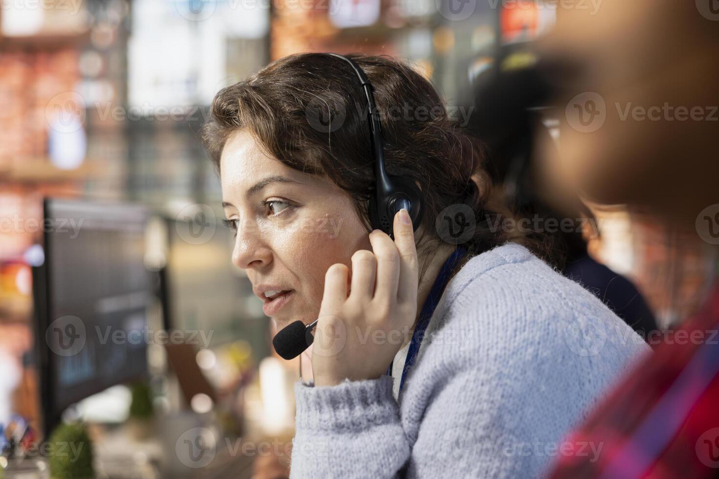 Customer service employee talking in headset mic, tracking support ticket in dedicated company software on PC. Call center worker creating support ticket for customer calling to solve issue photo
