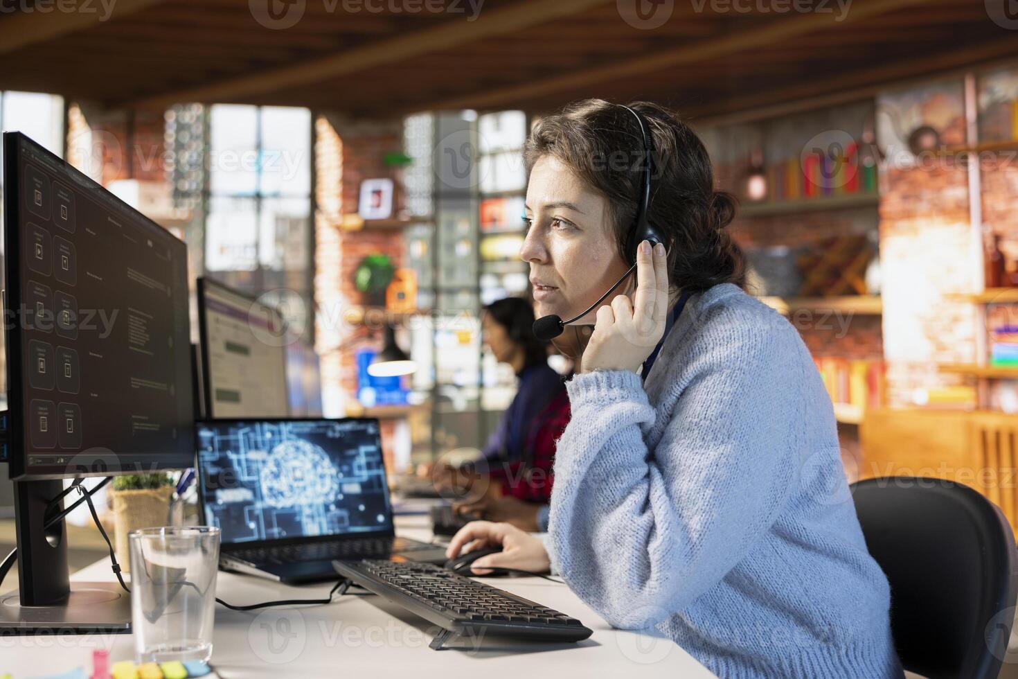 Call center worker wearing audio headset in office using AI to generate call scripts during conversation with customers. Woman doing customer support job using AI to summarize clients issues photo