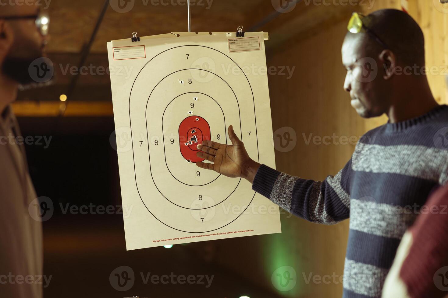 Shooting gallery worker teaching students how to hit bullseye with handguns. Firing range expert providing guide to achieve high level of proficiency with firearms while shooting targets photo