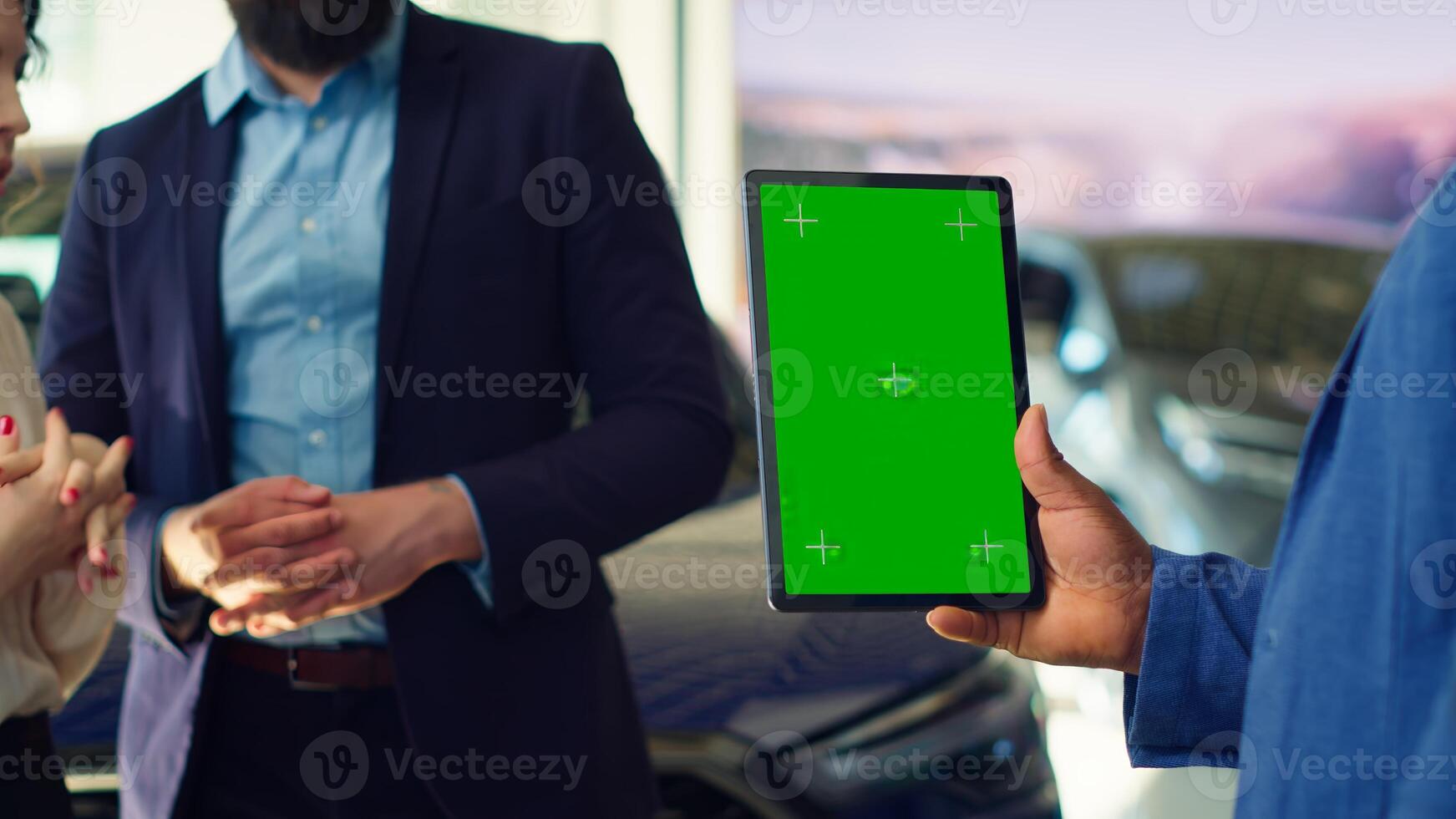 Salesman using green screen tablet to present car addons options to clients, trying to sway them make purchase. Showroom agent offers extended warranty to customers, holding mockup device, camera A photo