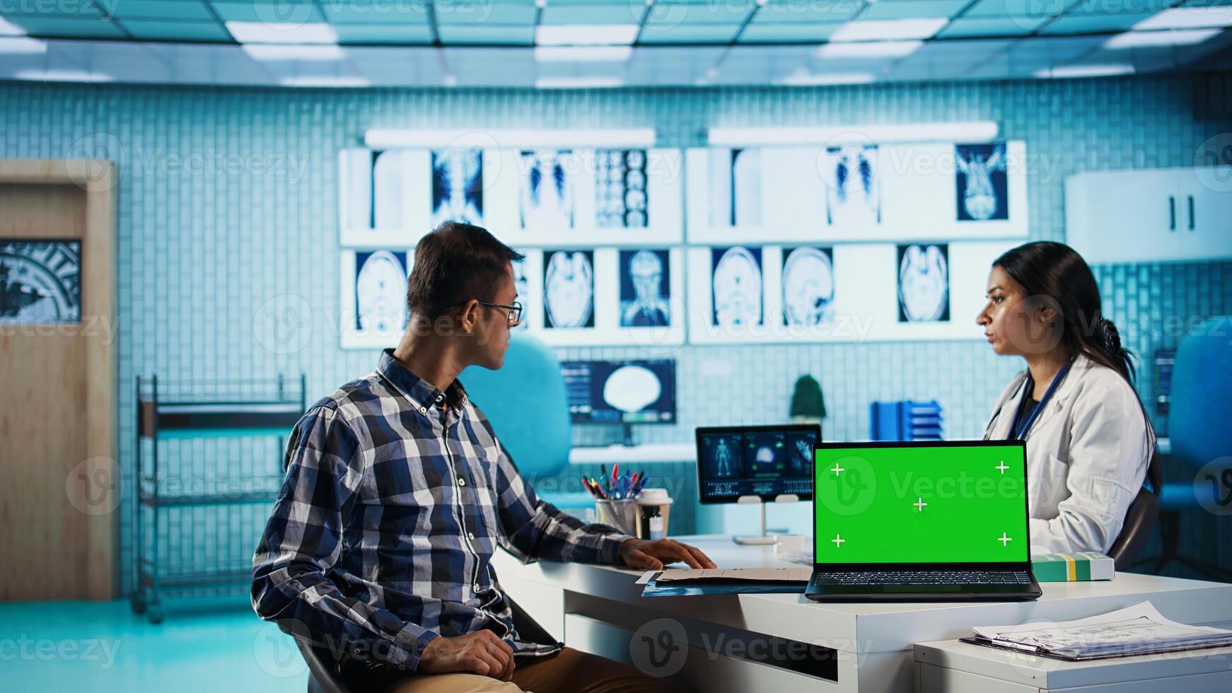 Indian medic consulting her patient in medical facility next to copy space, using advanced technology for scan interpretation and diagnostics. Expert gives advice based on records. Camera B. photo