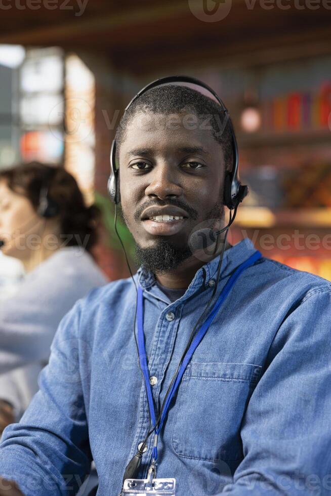 Portrait of smiling call center operator talking in audio headset mic, providing step by step guide to customer. Upbeat customer center employee speaking in headphones microphone, providing technical solutions photo