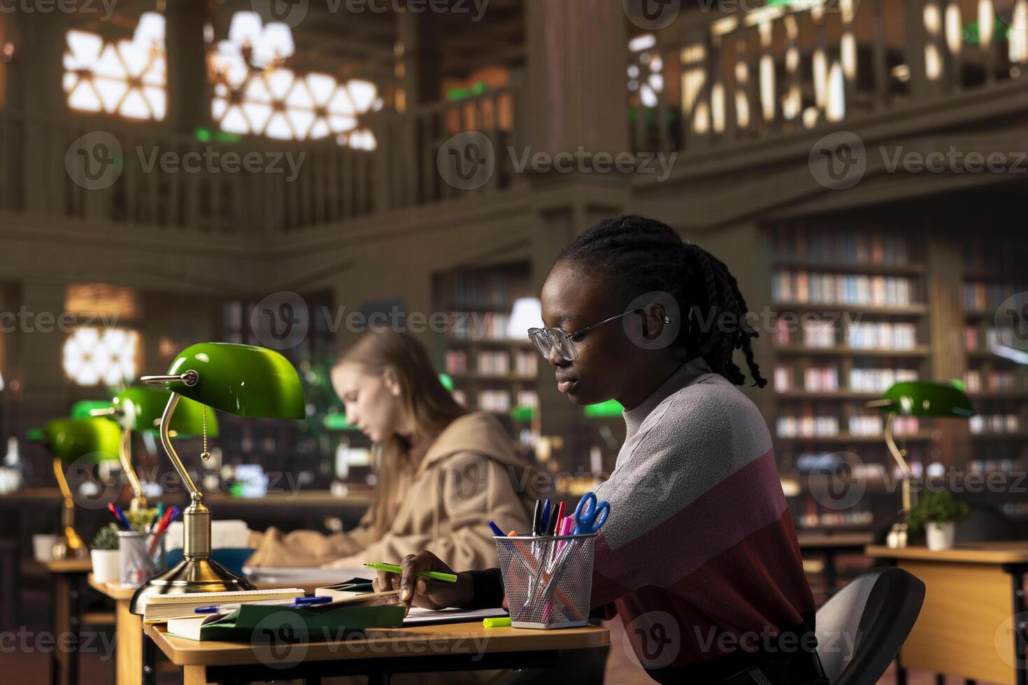 African american girl highlighting important handwritten class notes to integrate in her diploma paper with citations from reliable academic sources within the library database. Research collection. photo