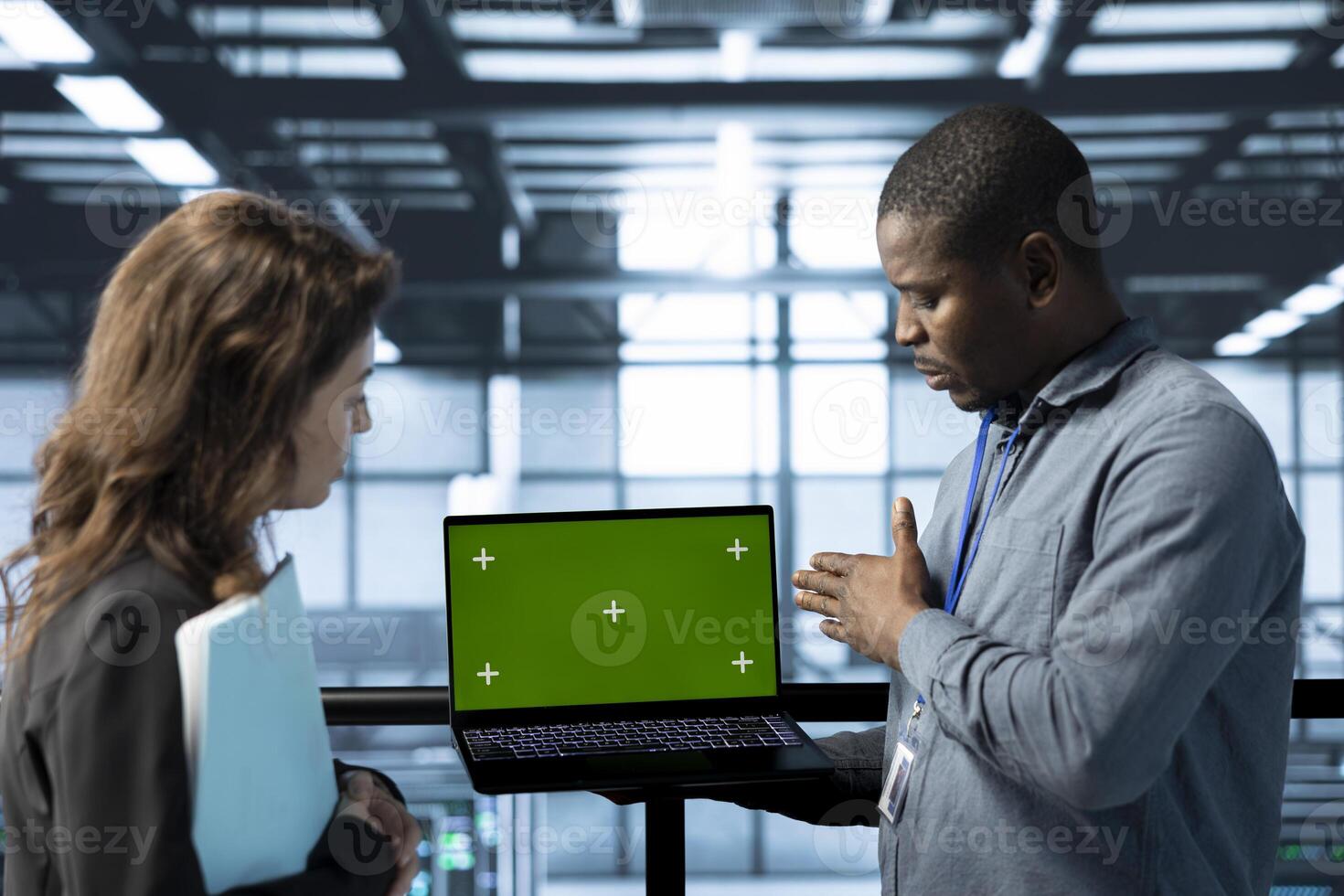 Engineers in data center using isolated screen notebook, observing analytics, reviewing equipment health. Workers using mockup laptop, adjusting system parameters, doing maintenance tasks photo