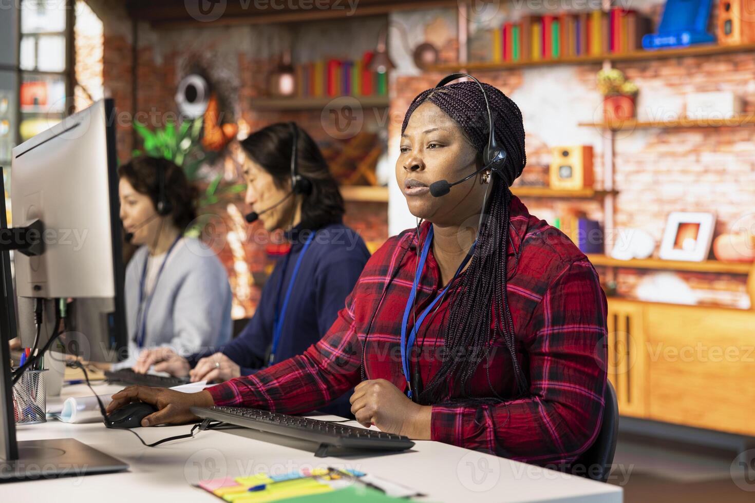 Teamworking call center colleagues in office helping customers by answering questions. Team of agents in customer support workplace in front of PC using headset mic to talk with clients photo