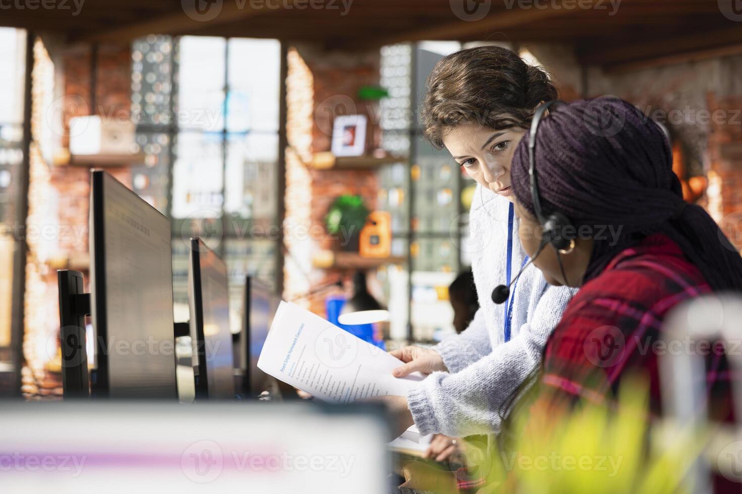 Call center onboarding specialist going over paperwork files with employee at PC desk. Customer support manager explaining company documentation to intern accommodating with job photo