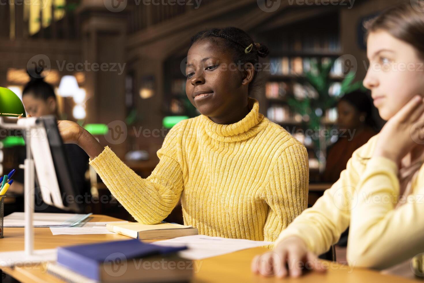 Elementary school pupils attending a live online course lesson from the library, connected via webcam to their educator in a modern academic session. Scholars discuss on a virtual webinar. photo