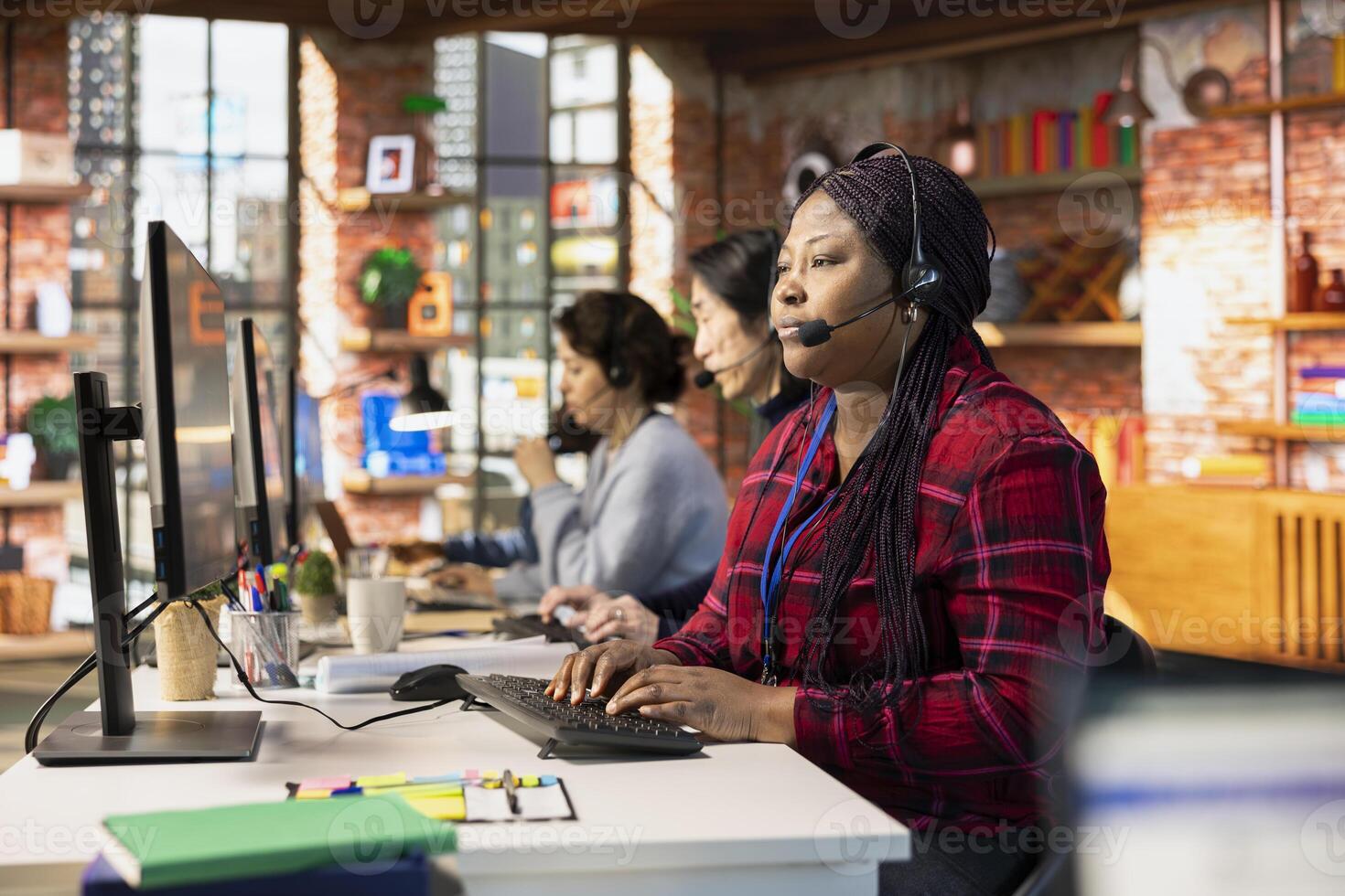 Call center agent in office talking in headset mic, communicating with customer, providing step by step guidance. Woman does customer support job at PC desk walking clients through technical solutions photo
