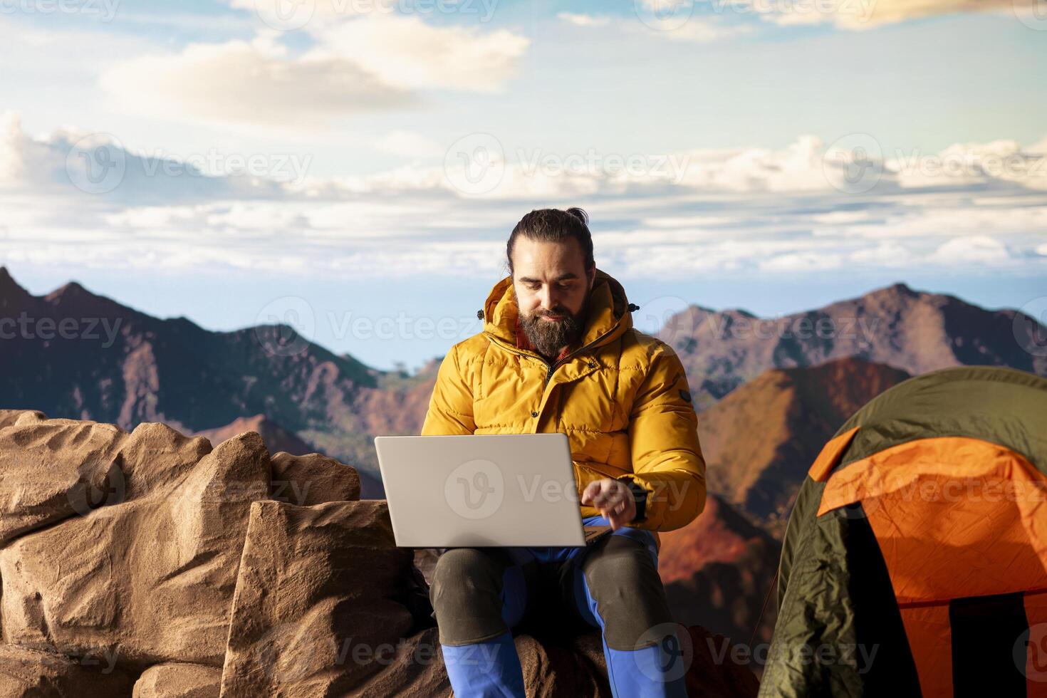 Young explorer keeps working at the top of the mountain with internet everywhere, enjoying global connectivity and productivity on the hill summit. High speed strong signal on a hike. photo