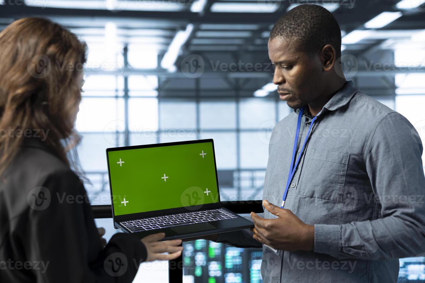 Team of engineers working in server farm, using green screen laptop to analyze data. Employees examining infrastructure in data center using mockup notebook, ensuring system integrity and security photo