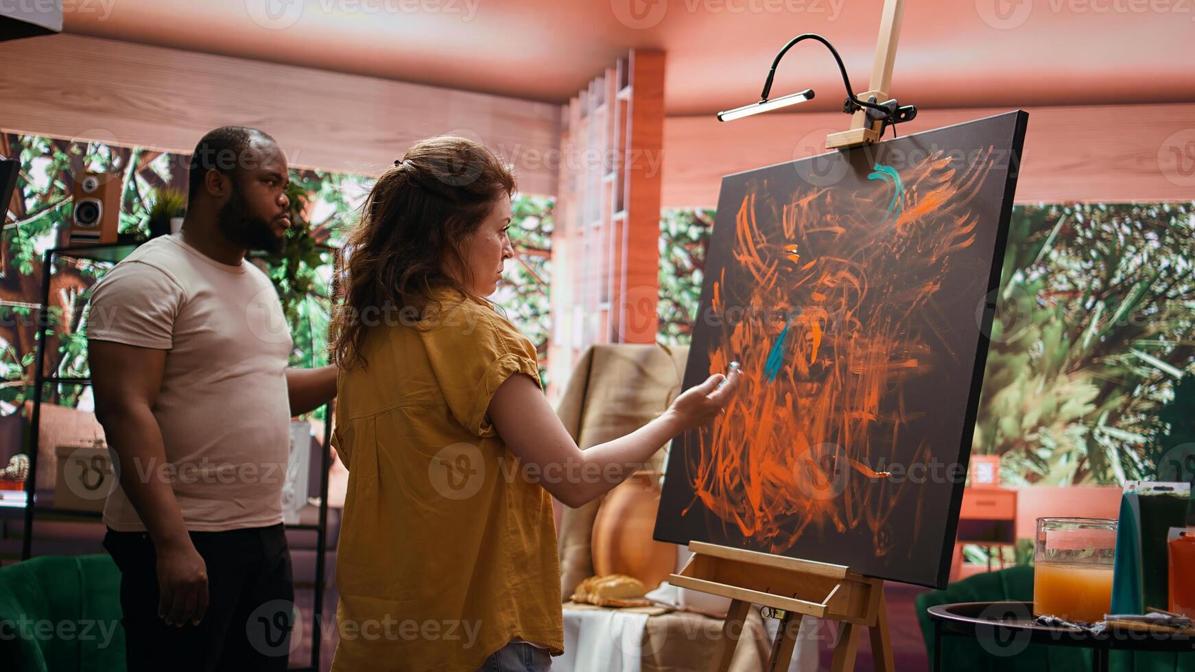 Team of artists in a gallery atelier working on new art piece, using finger painting technique for abstract creation. Blending acrylic paints with precision to create contemporary design. Camera B. photo