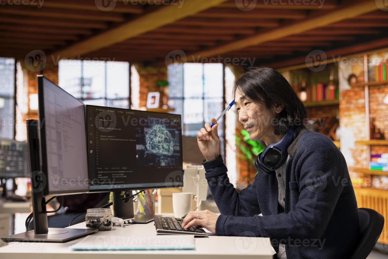 Software developer in small business workspace using computer to oversee artificial intelligence neural networks. Man in tech startup office using AI machine learning systems on PC photo