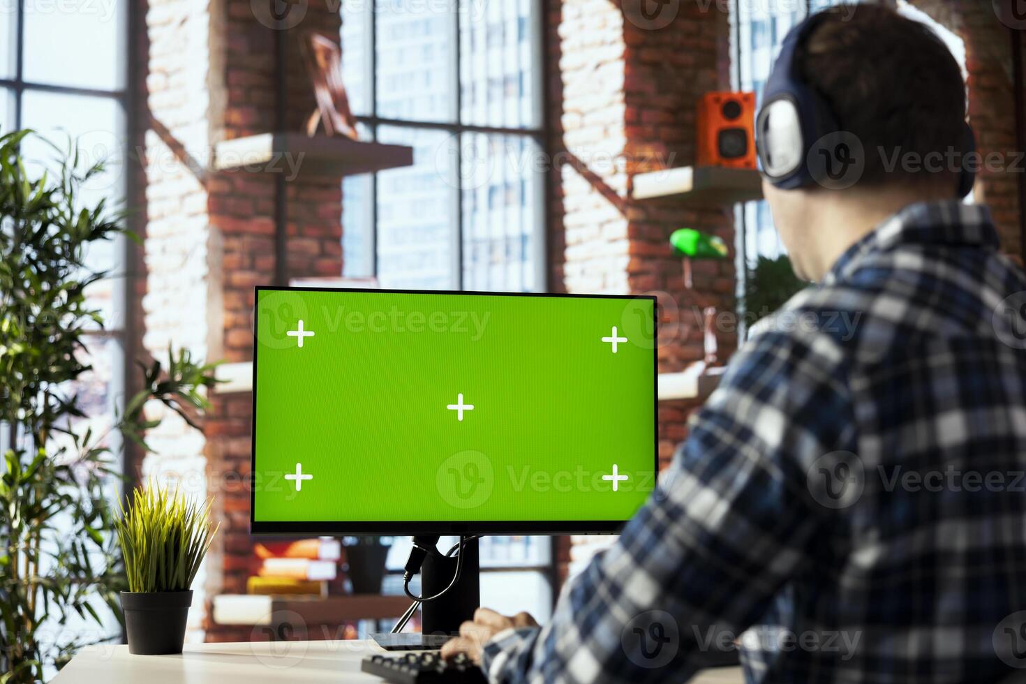 Man wearing headphones engaging in online training session on green screen PC, navigating course modules, watching instructional videos, completing quizzes, noting key concepts photo