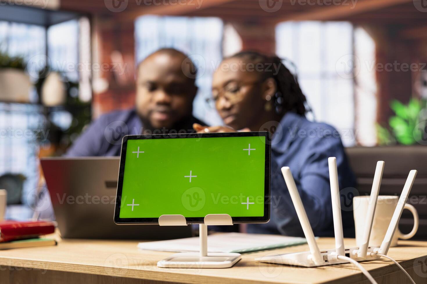 African American couple browse troubleshooting online guide next to chroma key, working together to debug router issues and restore their home network. Freelancers struggle to solve tasks. photo
