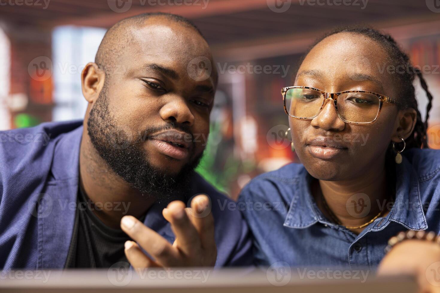 African american couple working remotely in their apartment, planning business strategies and discussing project development while using a laptop to track progress and ensure success. photo