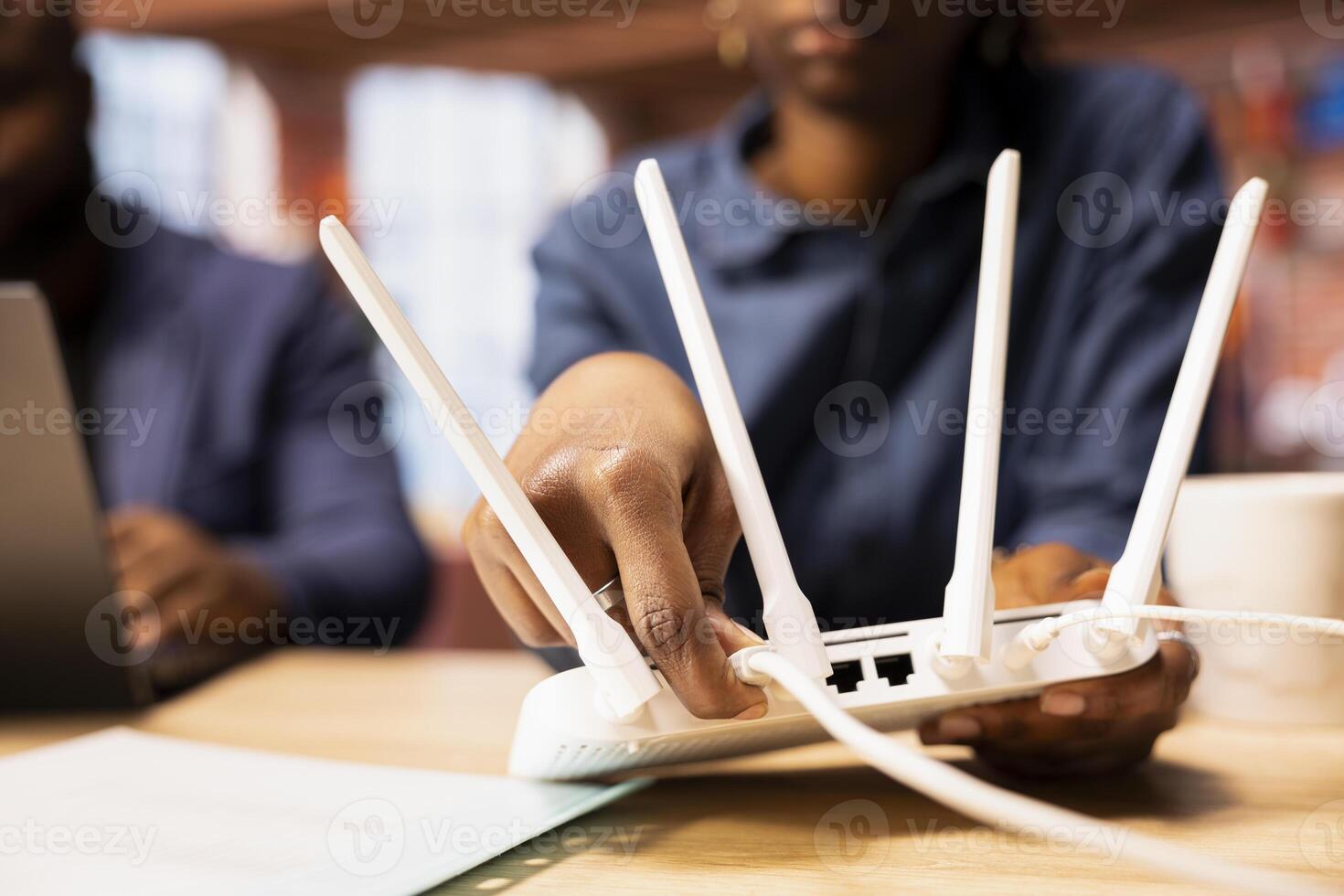 Black woman and man rebooting the WI FI router by moving the cables, troubleshooting to restore the internet connection. Freelancers at home struggling with signal loss or lag. photo
