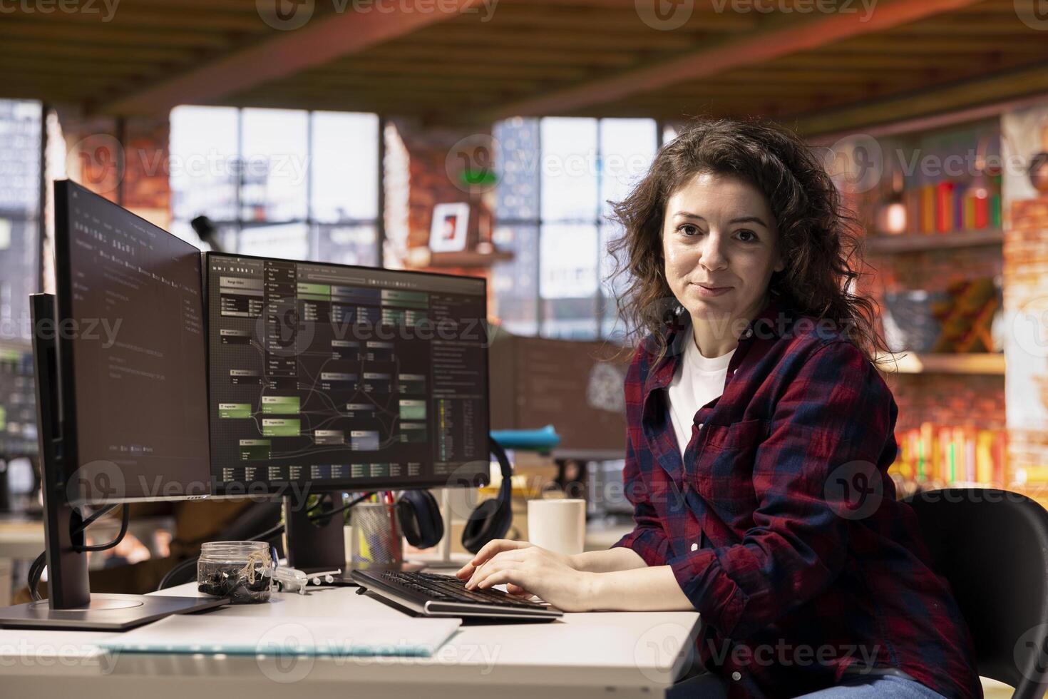 Portrait of smiling woman in startup office designing, coding and debugging applications in different software languages. Cheerful IT specialist doing code testing and quality assurance photo