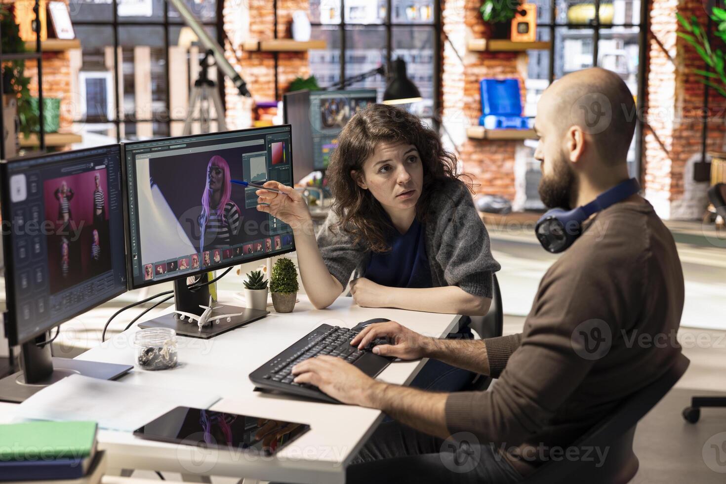 Professional photo editor interacts with AI chatbot and retouching software on dual monitors, using machine learning tools to generate high quality images. Photography industry with automation.