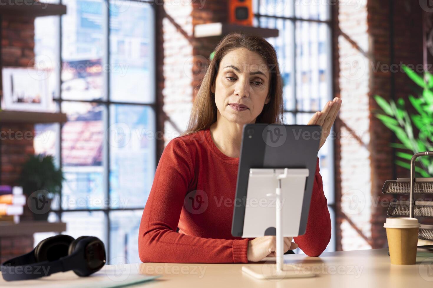 Focused person smiling and waving during a web conference at her home, showcasing virtual meeting and online communication in a digital and wireless lifestyle. Conference speaker. photo