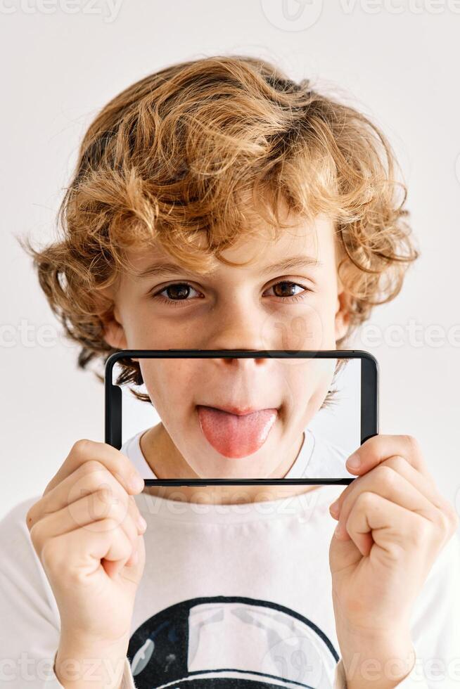 Child posing with his mobile phone and photos made of parts of his face