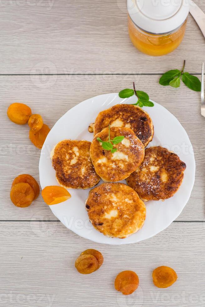 Quick and easy breakfast.Fresh cottage cheese pancakes with pieces of dried apricots and a leaf of mint photo