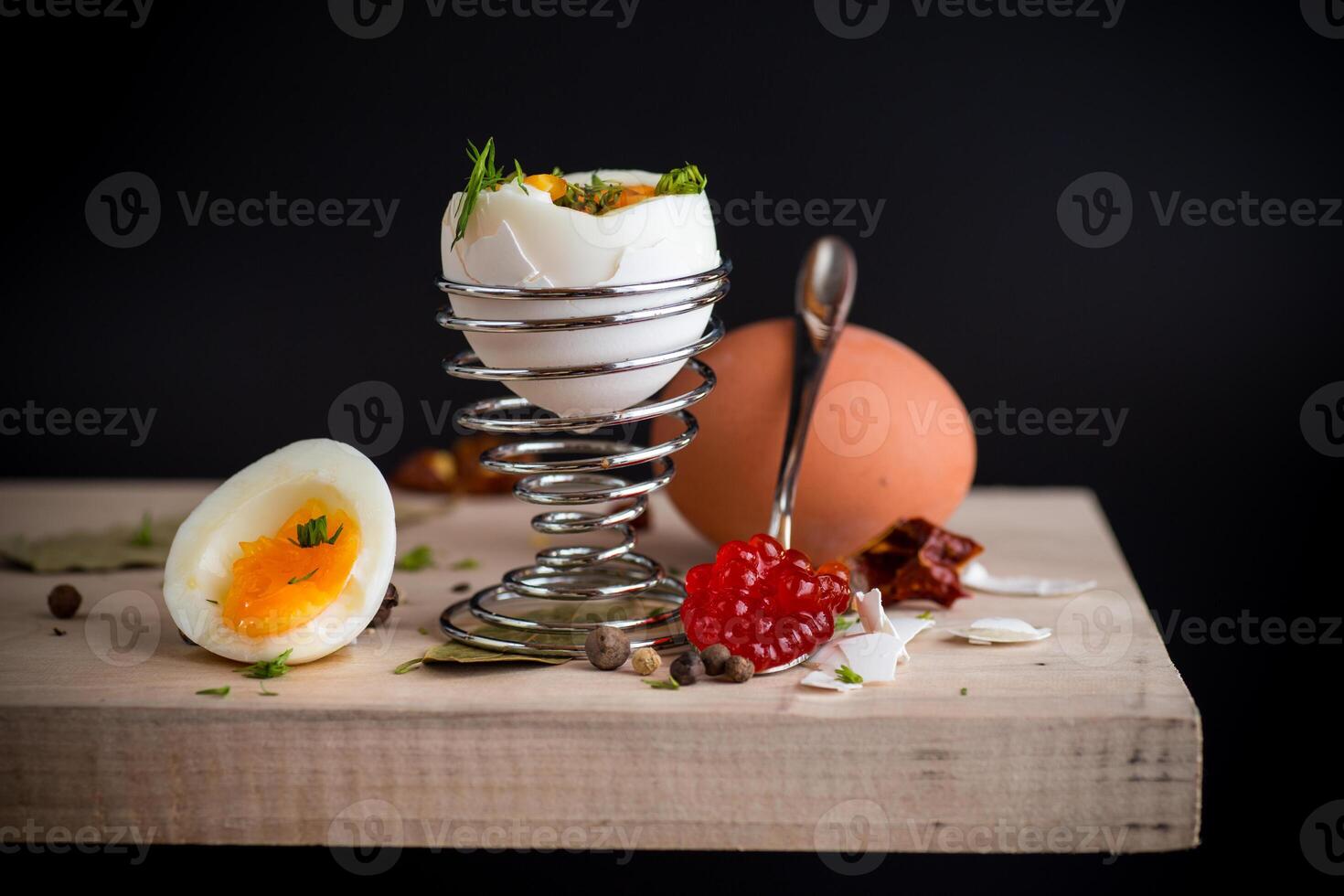Quick and easy breakfast.red caviar in a spoon and morning boiled egg for breakfast, isolated on black background photo