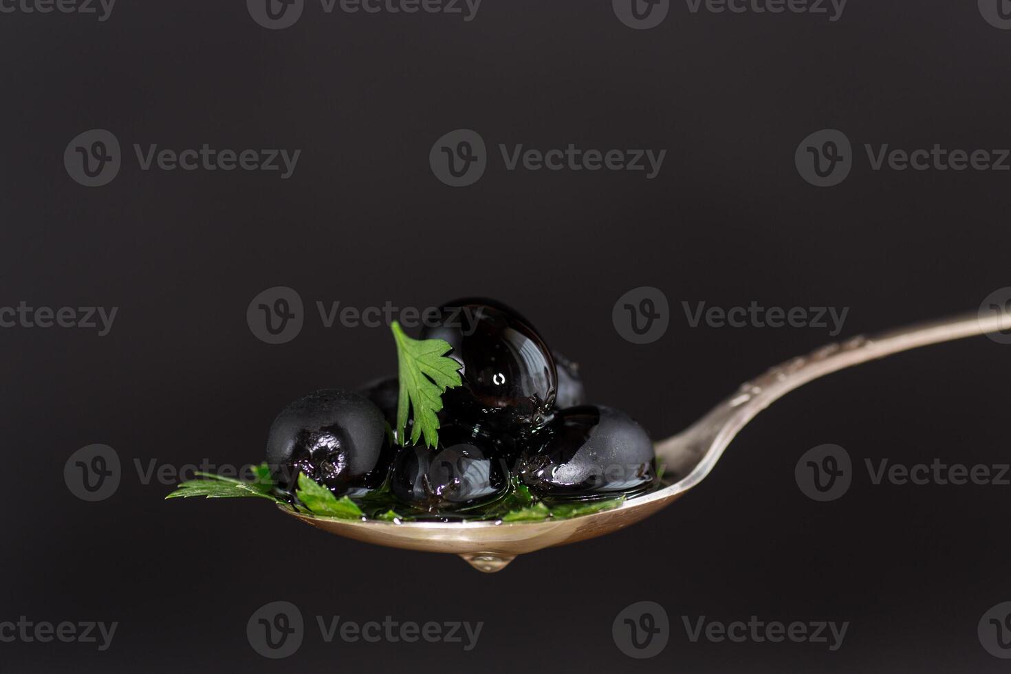 Black shiny olives in a spoon. photo