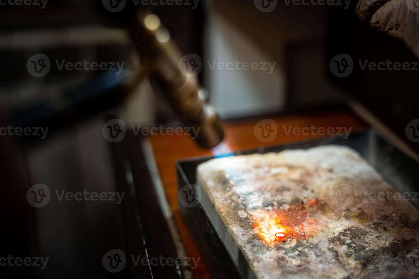 Jeweler melting silver metal with open flame blow torch welding photo