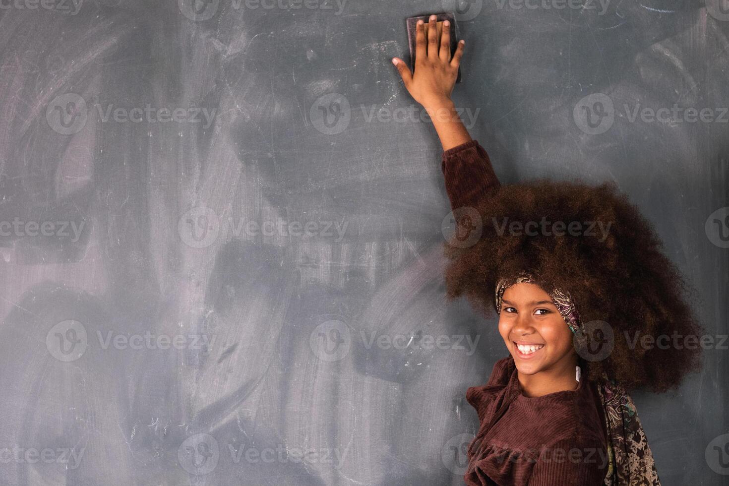 Black girl writing on chalkboard in classroom photo