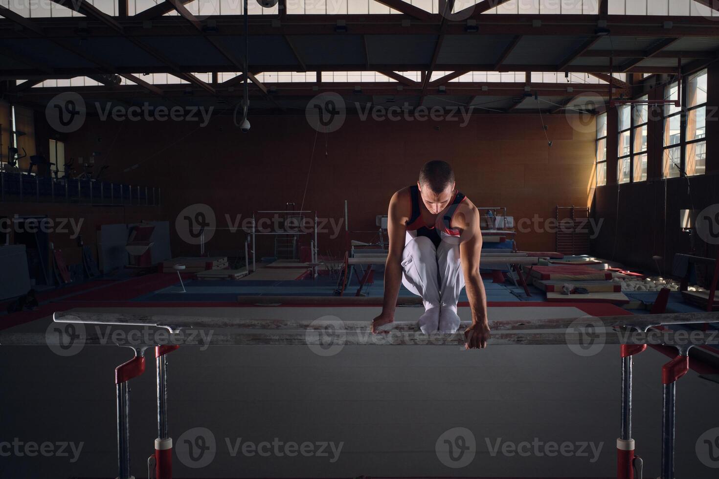 Young male gymnast doing exercises on the parallel apparatus. photo