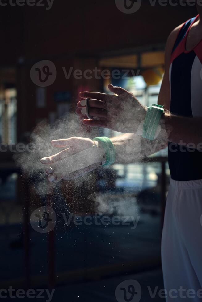 Unrecognizable sportsman preparing himself by putting magnesium in his hands to do the exercises of sport gymnastics. photo