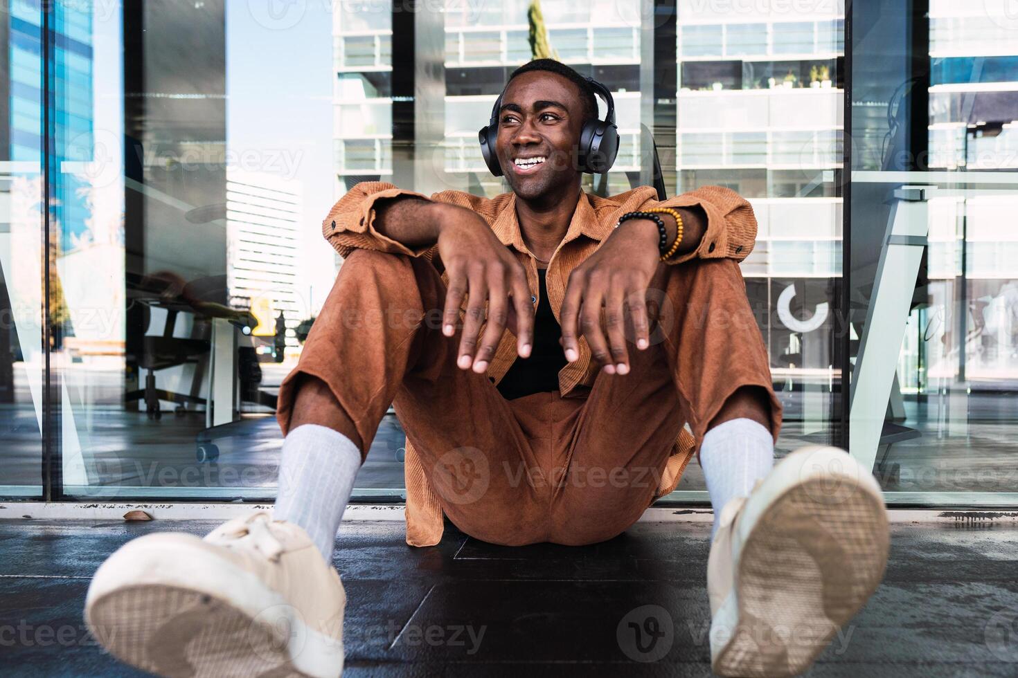 Black man listening to music near building photo