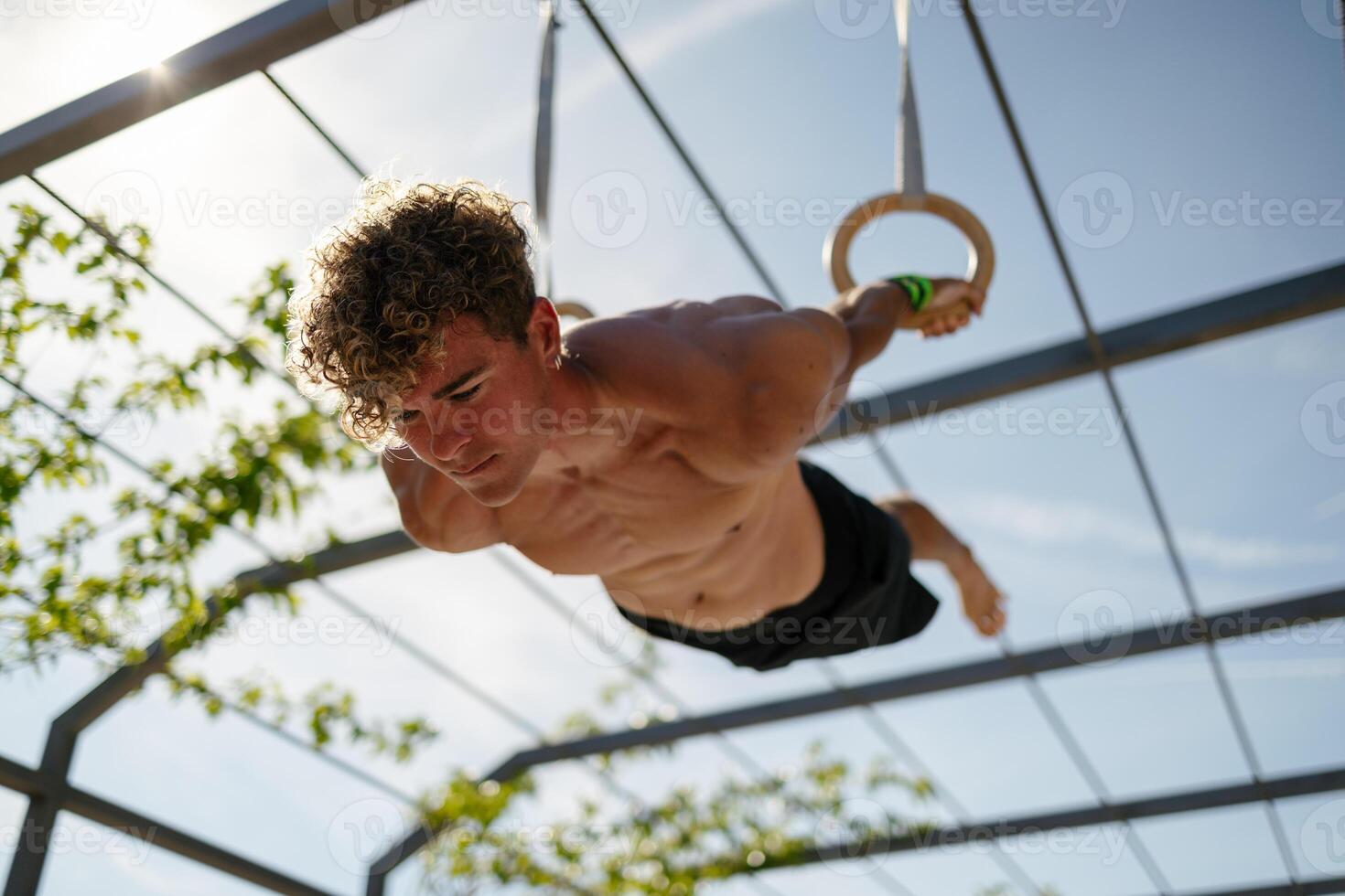 Strong young sportsman exercising with rings photo