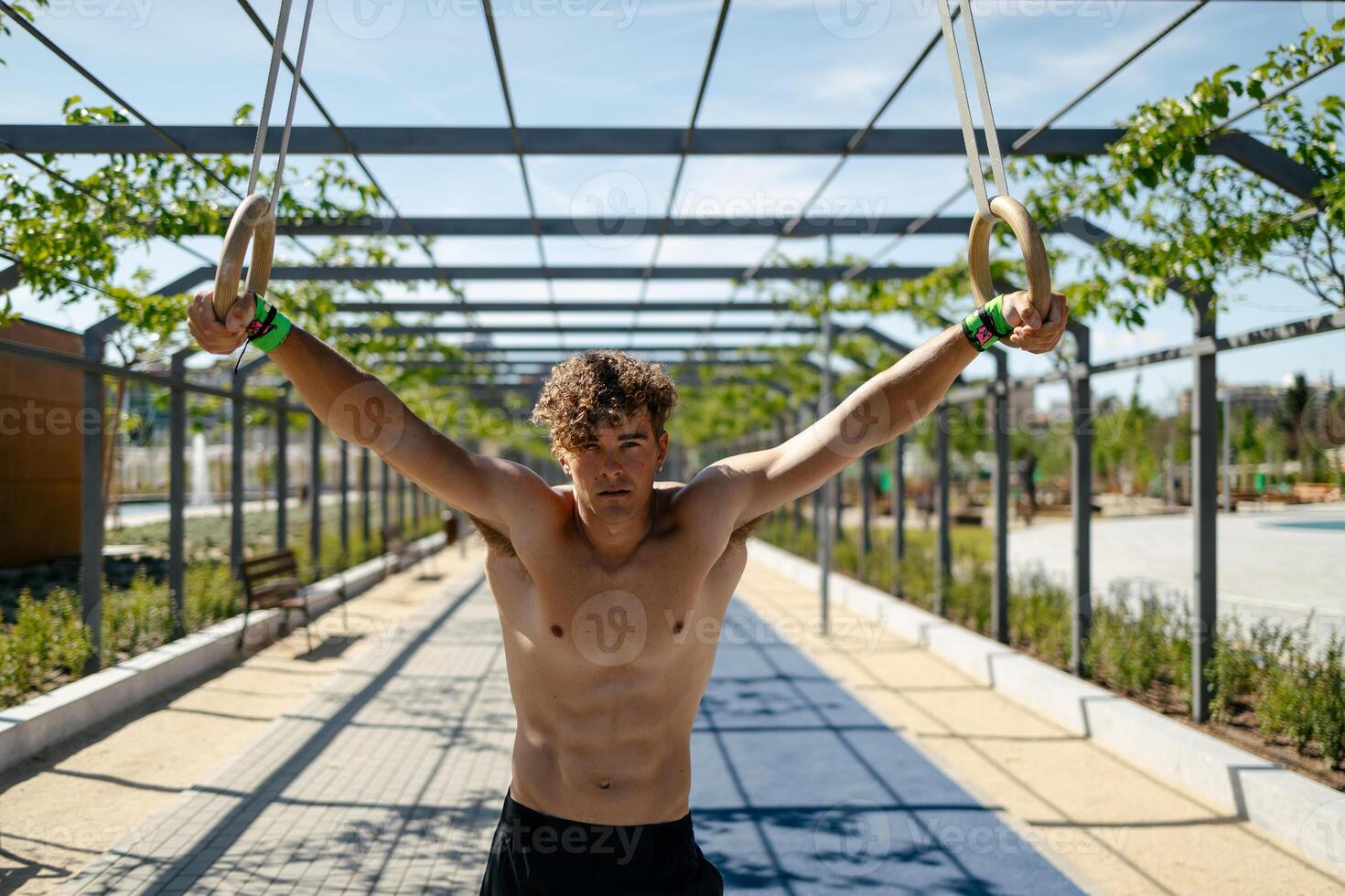 Strong young sportsman exercising with rings photo