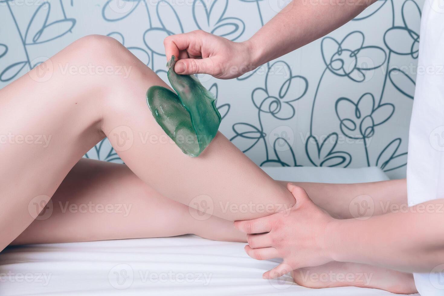 Beautician hands doing depilation in woman legs with hot wax photo