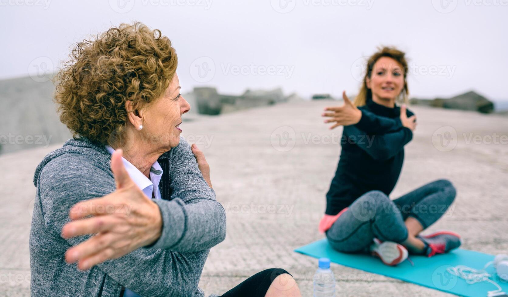 Senior woman stretching with coach photo