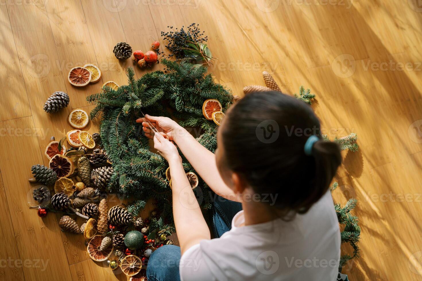 Designer ties a frame of a Christmas wreath of spruce branches with a string. Top view photo