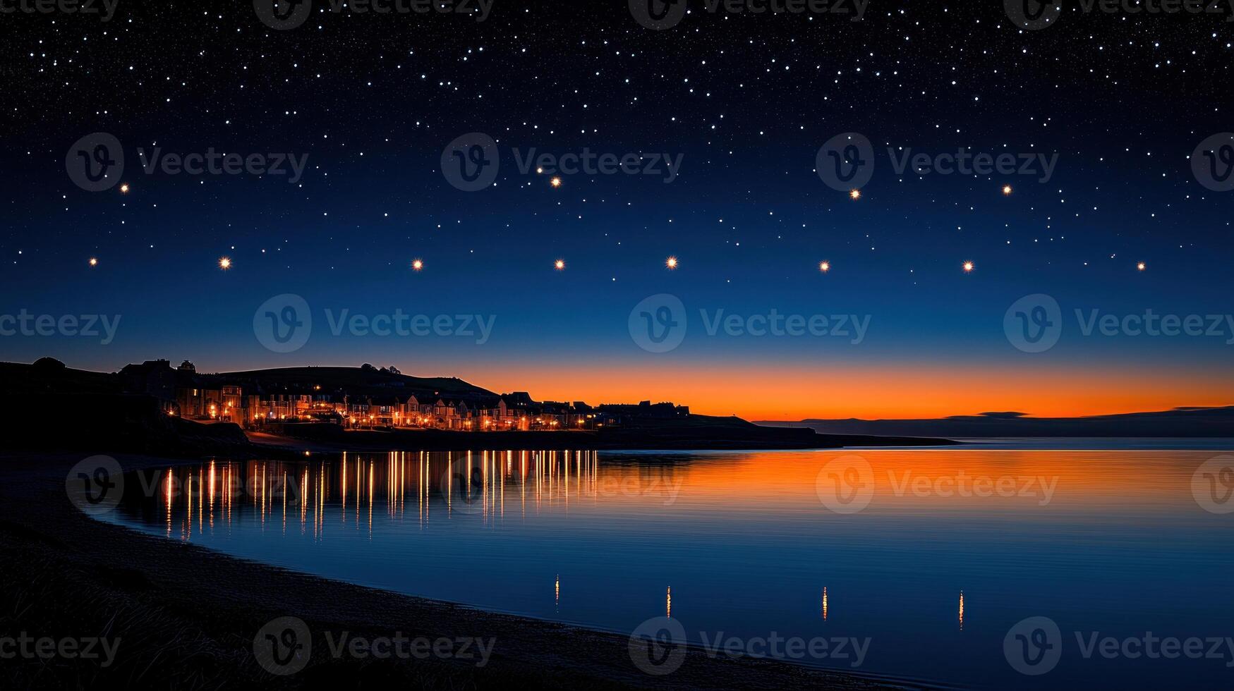 Night sky over coastal town with lights reflecting on calm water. photo
