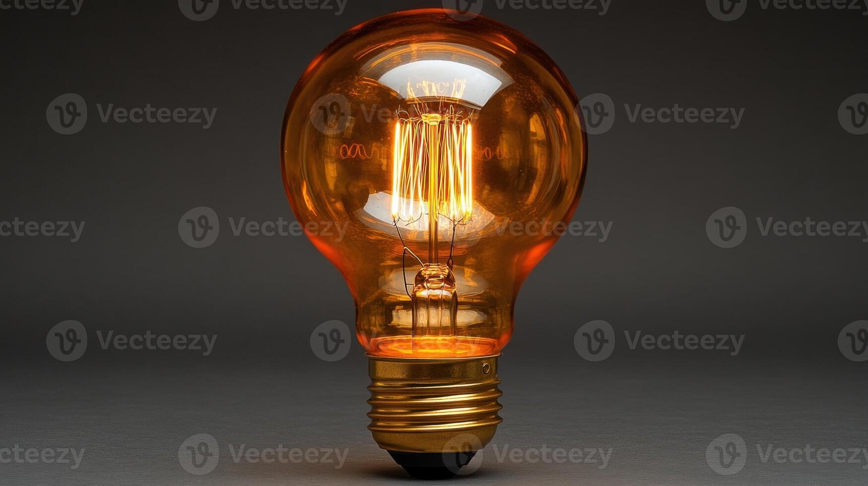 Glowing amber Edison light bulb on dark background. photo