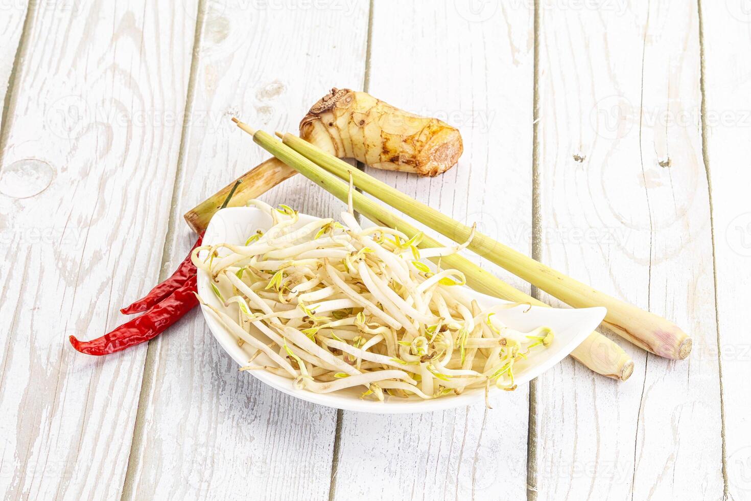 A bowl of noodles with a stick of ginger and a red chili photo
