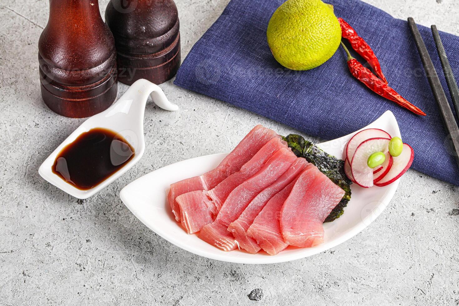 A plate with sliced tuna, chopsticks and a bottle of beer photo