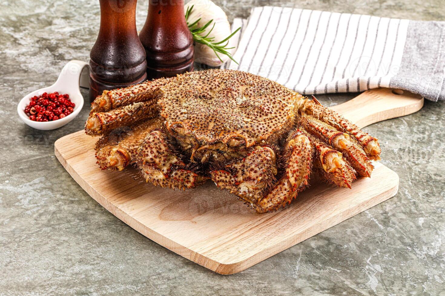 A crab on a cutting board with a knife and pepper photo
