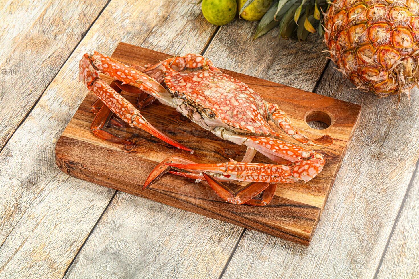 A crab on a cutting board with pineapple and other fruit photo